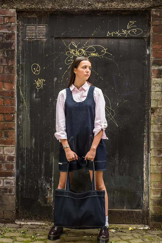 image of fashionable lady dressed in clothes from Never Make Waste standing outside disused shop Underbanks, Stockport